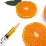 Close up medical injection syringe needle with orange leaf pieces on white background, concept cosmetic, fruit, vitamin C, natural, organic, beauty, treatment, intravenous, frame, wallpaper